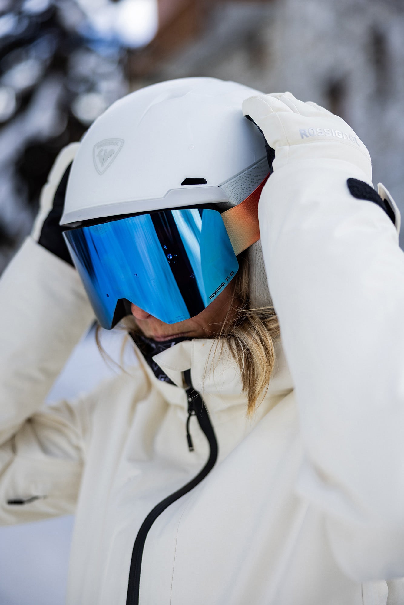 Person wearing a white helmet with a blue visor and a white jacket in a snowy environment.